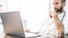   Person sitting at a desk looking at a laptop