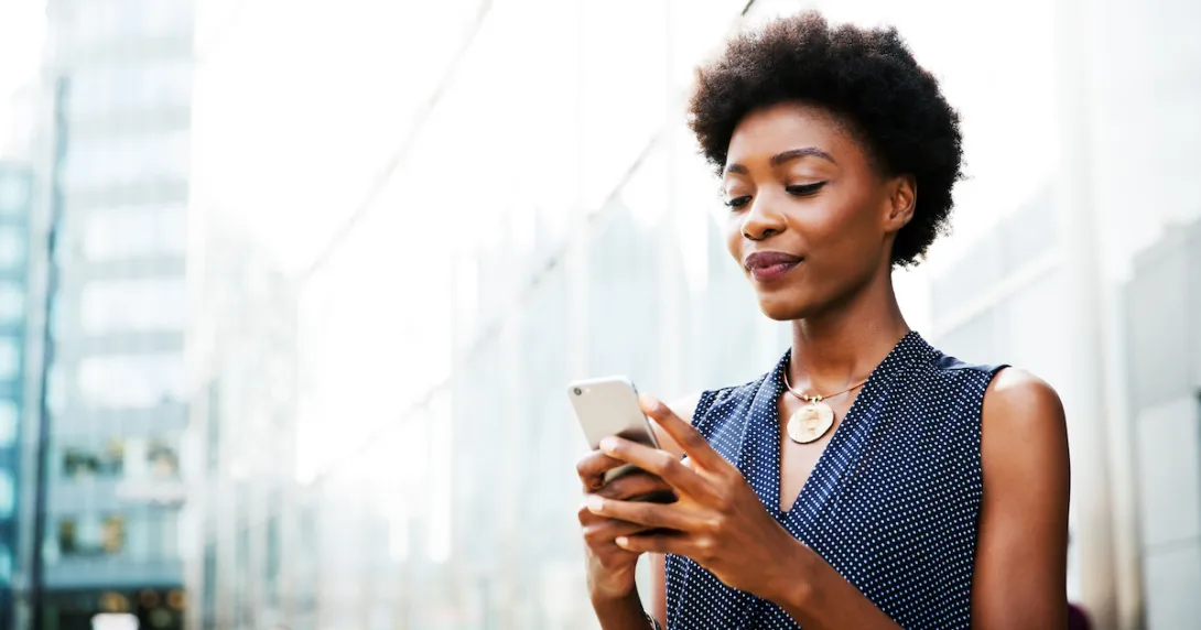 Person standing on a city block looking at their phone