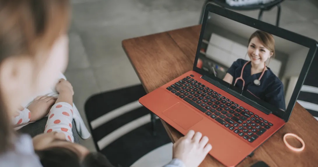 
  Two people sitting down while looking at a computer with a healthcare provider on the screen
