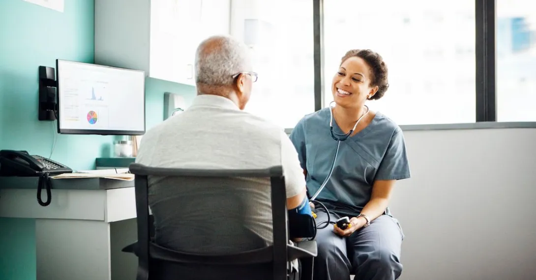 
  A provider talking to a patient while taking his blood pressure. 
